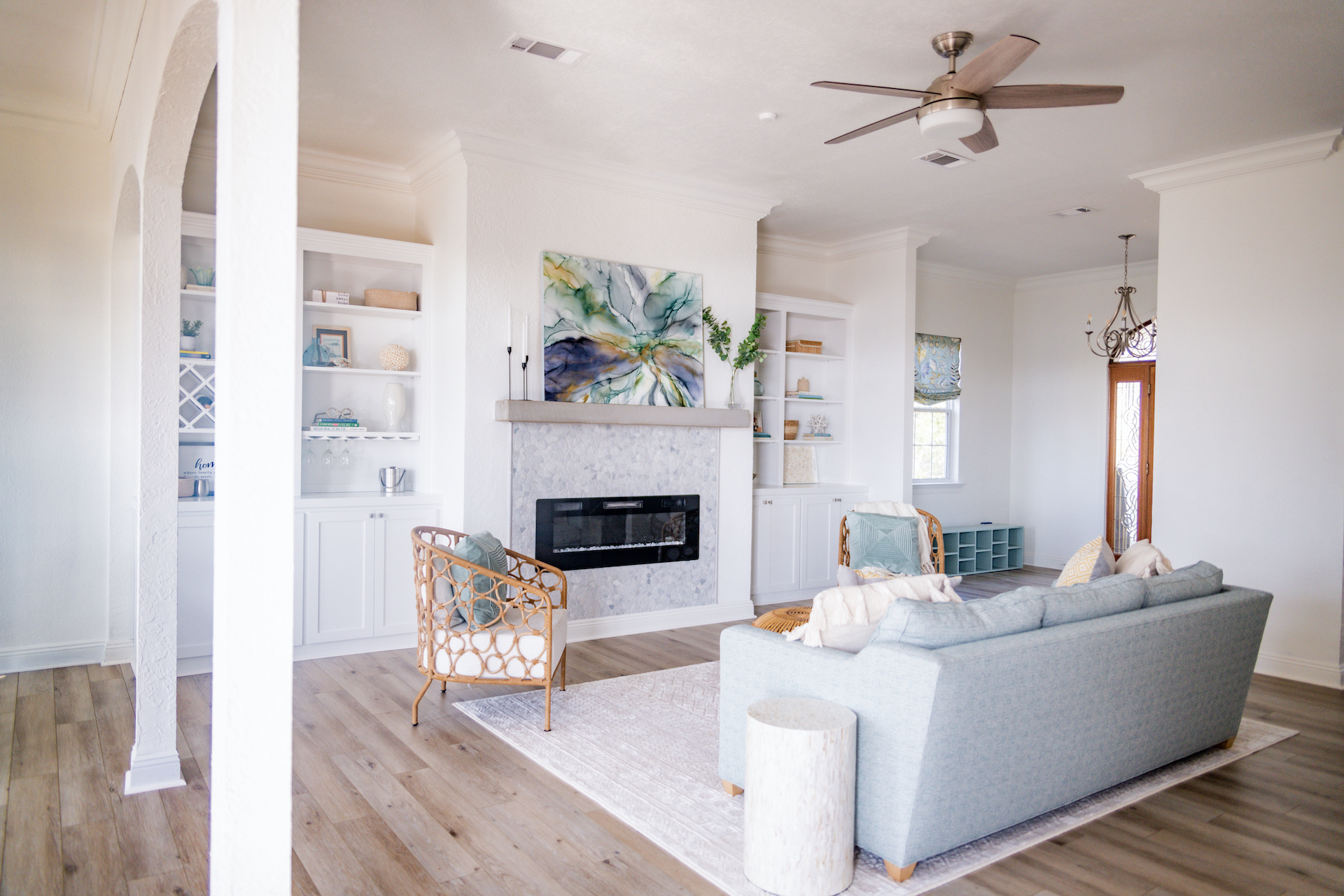 Contemporary Coastal living room with white walls, blue couch, and electric fireplace.