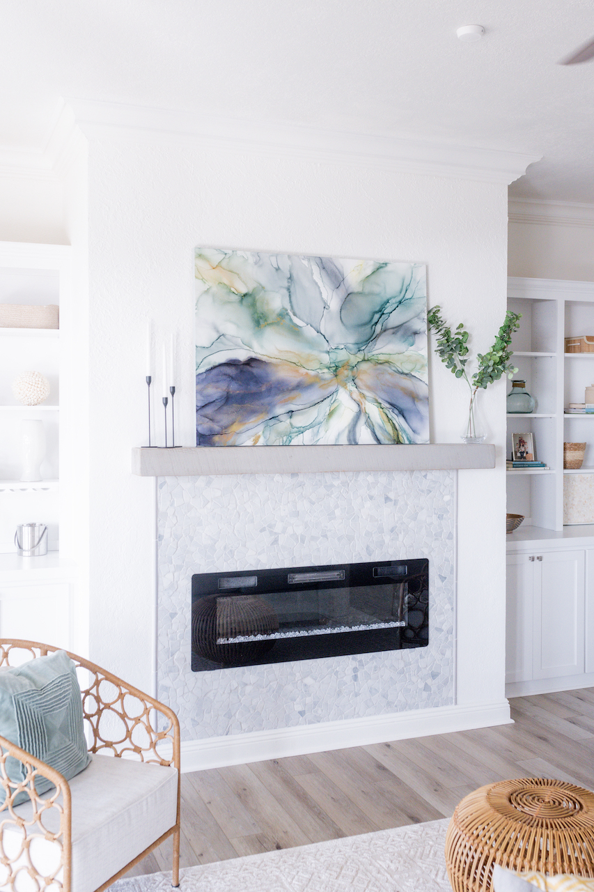 electric fireplace in a coastal living room with art above it