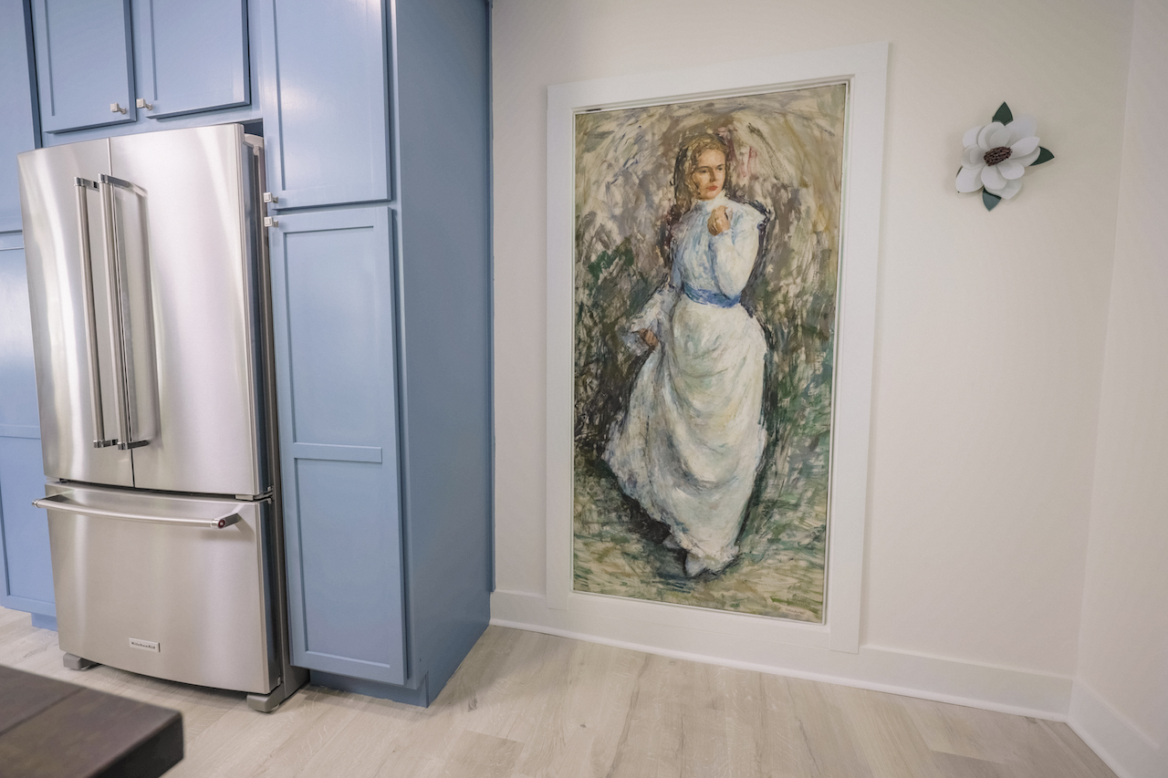 blue kitchen cabinets with a painting that serves as a secret door between the kitchen and office