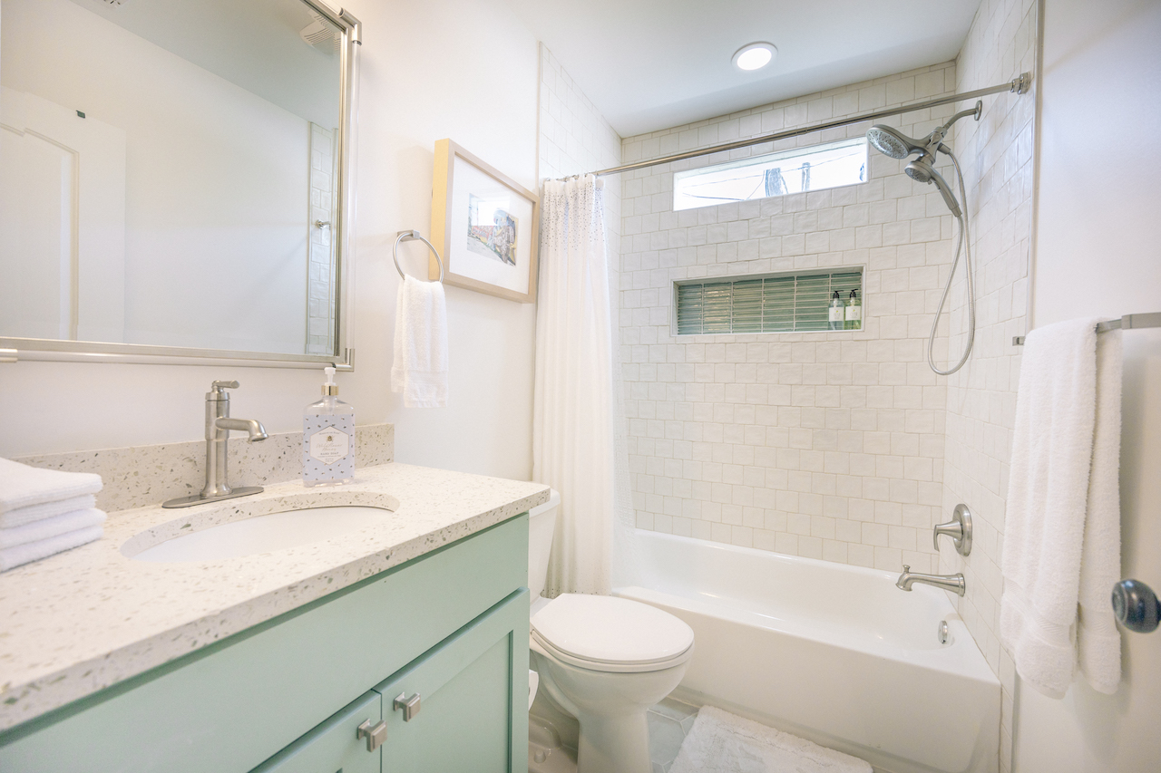 coastal bathroom with white square tile and blue green glass niche tile