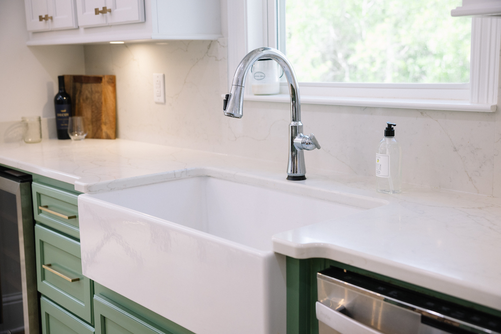 white farmhouse sink with green cabinets
