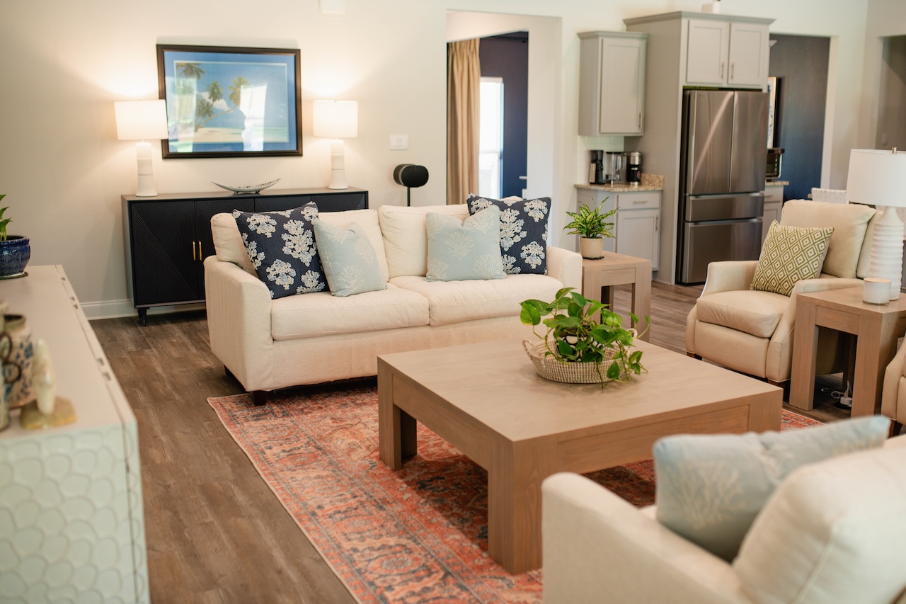 Living room with white couch, blue pillows and a red rug